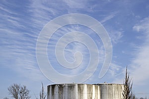 Clear blue sky with light gentle clouds over an industrial building in winter