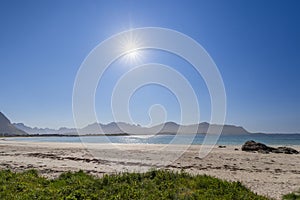 Clear blue sky over Jusnesvika Bay with the sun shining brightly, white sandy Rambergstranda beach in the foreground