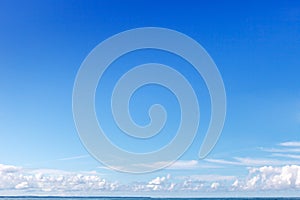 Clear blue sky and small white clouds on the horizon