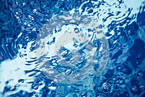 Clear blue water with bubbles and ripples in swimming pool