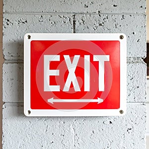 Red Exit Sign with Directional Arrows on a Concrete Wall