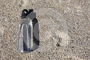 A clear bottle of water lies on the sand. photo