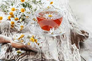 A clear Cup of medicinal chamomile tea on an old wooden table. Health and healthy lifestyle concept