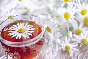 A clear Cup of medicinal chamomile tea on an old wooden table. Health and healthy lifestyle concept