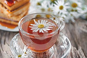 A clear Cup of medicinal chamomile tea on an old wooden table. Health and healthy lifestyle concept