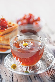 A clear Cup of medicinal chamomile tea on an old wooden table. Health and healthy lifestyle concept