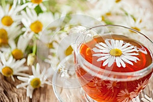 A clear Cup of medicinal chamomile tea on an old wooden table. Health and healthy lifestyle concept