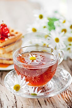 A clear Cup of medicinal chamomile tea on an old wooden table. Health and healthy lifestyle concept