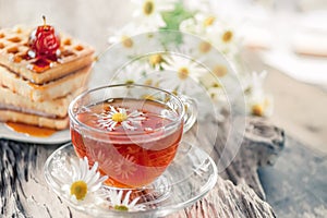 A clear Cup of medicinal chamomile tea on an old wooden table. Health and healthy lifestyle concept