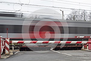A clear electric train against the background of a closed barrier, road safety