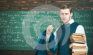 Clear explanation. Teacher formal wear and glasses looks smart, chalkboard background. Man in end of lesson takes off