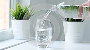 Clear fresh drinking pure water poured Into glass from bottle. Slow motion