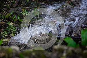 Clear and fresh mountain spring water flows and splashes over a stone - Macro photo of the cold and clear water drop