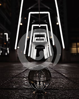 Clear glass ball on the ground reflects the glowing frames of a tunnel corridor at night