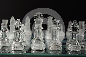 Clear glass chess pieces on a glass chessboard