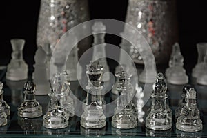 Clear glass chess pieces on a glass chessboard