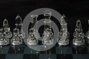 Clear glass chess pieces on a glass chessboard isolated