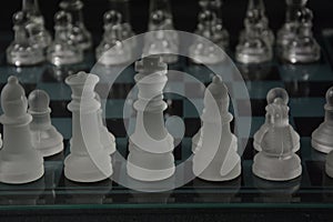 Clear glass chess pieces on a glass chessboard isolated