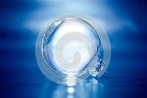 Clear glass Christmas ornament on blue background with empty space