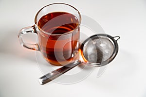 Clear glass cup of hot ceylon black tea in a mug & tea strainer