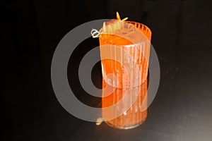 Clear glass of decorated orange alcoholic drink with ice