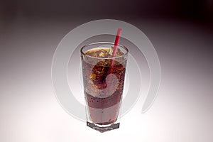 Clear glass with ice and soda with red straw