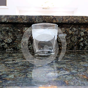 Clear glass with ice and water on a marble counter