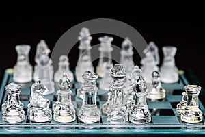 glass, transparent chess pieces on a checkerboard, selective focus, close-up, isolated on black