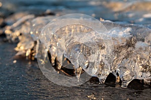 Clear ice icicle close-up sparkling on frozen lake