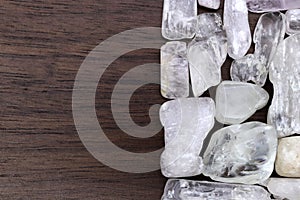 Clear kunzite heap stones texture on half brown varnished wood background. Place for text