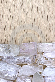 Clear kunzite heap stones texture on half light varnished wood background. Place for text