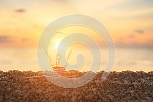 Clear light bulb on sunset beach, energy concept