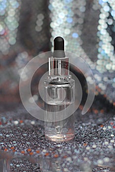 Clear liquid in glass bottle with dropper on grey shining background.Skincare essence for beautiful healthy skin