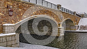 Clear Panorama Stone arched bridge with lamps over a lake during winter in Daybreak Utah