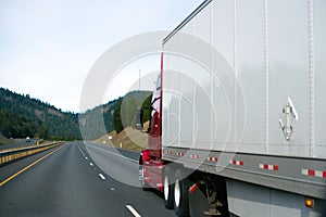 Clear red big rig semi truck white dry van trailer in perspective road sky