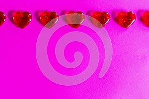 Clear red hearts aligned at top of image as border on pink background