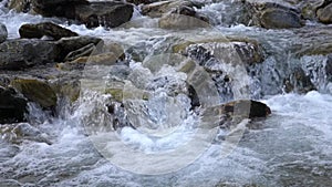 Clear river water flowing by the rocks with splashes, slow motion