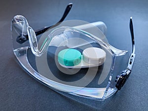 clear safety glasses, clear solution bottle and contact lens container.