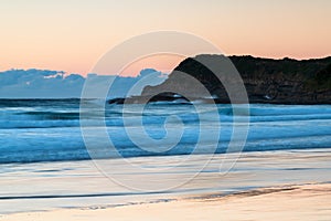 Clear skies sunrise seascape with waves and a low cloud bank on the horizon