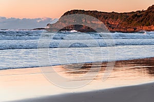 Clear skies sunrise seascape with waves and a low cloud bank on the horizon