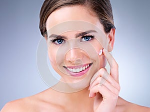 Clear skin is possible. a young woman applying moisturizer to her face.