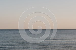 Clear sky and sea at sunset, unidentified sailboat in the distance on horizon