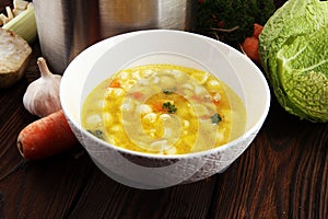 Clear soup with chicken and noodles. Broth with carrots, onions various fresh vegetables in a pot