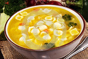 Clear soup with chicken and noodles. Broth with carrots, onions various fresh vegetables in a pot