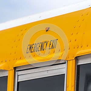 Clear Square Close up of the exterior of a yellow school bus with an Emergency Exit sign