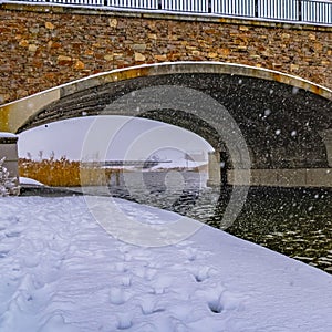 Clear Square Snowy trail along lake and passing under a bridge