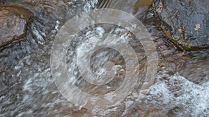 Clear stream running through stone boulders Abundant river flowing on stone bottom in slow motion.