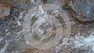 Clear stream running through stone boulders Abundant river flowing on stone bottom in slow motion.