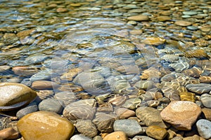 clear stream water flowing over smooth rocks