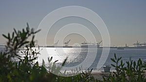 Clear sunny day in California. View of the cargo port at Long Beach USA. Sun glare on the birch water of the ocean.